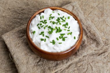 Cottage cheese with chives in wooden bowl